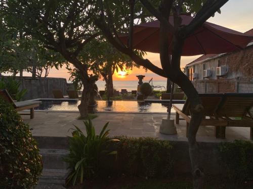 un tramonto su una piscina con una panchina e un ombrellone di Bintang Beach Villa ad Amed