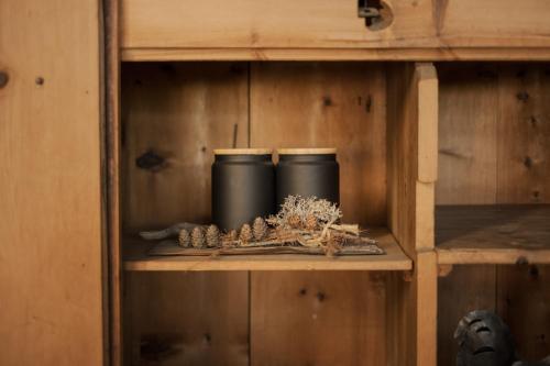 a shelf with three black cups and pine cones at Apartments Moarhof in Feldthurns