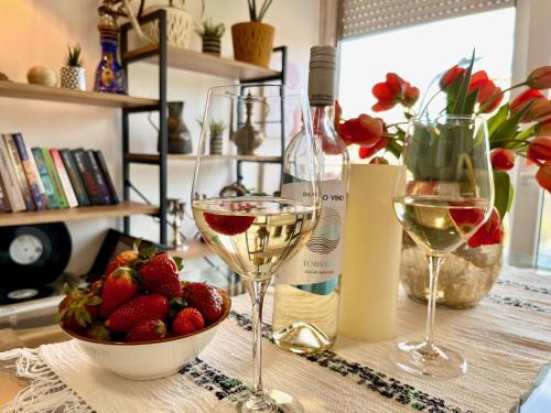a table with two glasses of wine and a bowl of strawberries at Stay in Skopje - Prime Location Apartment in Skopje