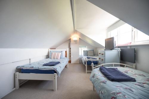 a attic room with two beds and a tv at Y Lleiaf in Holyhead