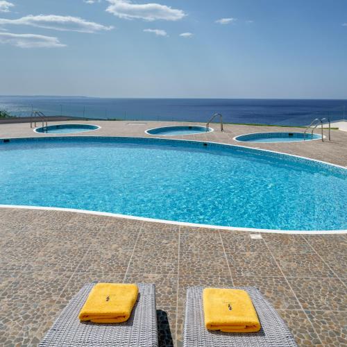 a swimming pool with two yellow benches next to it at Beachfront Villa Atalandia with Heated Pool, Gym, BBQ & Office in Goúdhouros