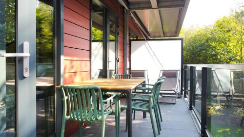a patio with a wooden table and green chairs at Hike & Bike Hotel in Noordwolde
