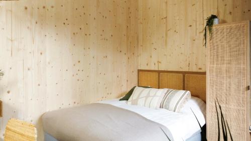 a bed in a room with a wooden wall at Hike & Bike Hotel in Noordwolde
