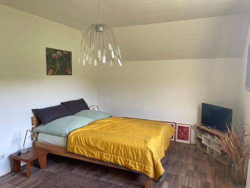 une chambre avec un lit avec une couverture jaune dans l'établissement La Maison des Roses, à Drachenbronn-Birlenbach