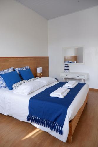 a bedroom with a large bed with blue and white pillows at Casa do Vale das Furnas in Furnas