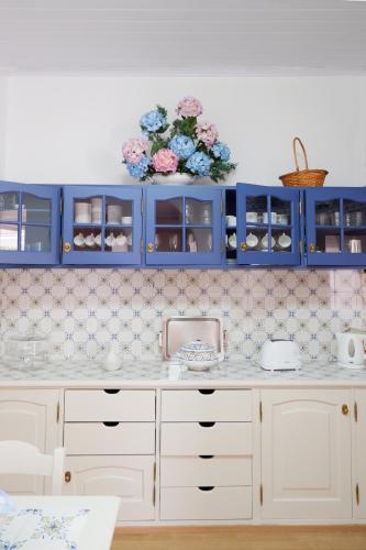 a kitchen with blue cabinets and flowers on the wall at Casa do Vale das Furnas in Furnas