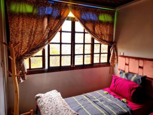 a bedroom with a window with a bed and a window at Gite akswal amssakrou in Ikis