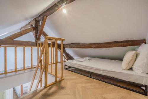 Ce lit se trouve dans un dortoir doté de poutres apparentes. dans l'établissement Appartement Mezzanine proche Atelier des lumières, à Paris