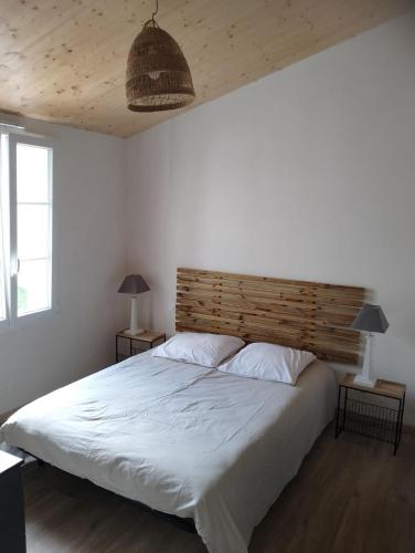 une chambre avec un grand lit avec une tête de lit en bois dans l'établissement maison 6-8 personnes, 300m de la plage, à La Guérinière