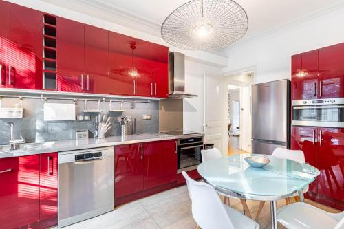 une cuisine avec des placards rouges et une table en verre dans l'établissement GuestReady - Spacieux Appartement idéal pour 6, à Paris