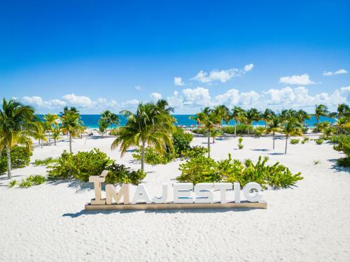 a sign on a beach with palm trees and the ocean at Majestic Elegance Costa Mujeres - All Inclusive in Cancún
