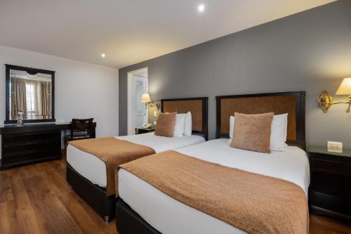 a hotel room with two beds and a desk at Hotel Le Manoir Bogotá in Bogotá