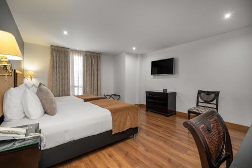 a hotel room with a bed and a television at Hotel Le Manoir Bogotá in Bogotá
