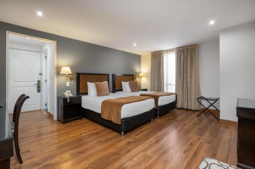 a hotel room with a large bed and wooden floors at Hotel Le Manoir Bogotá in Bogotá