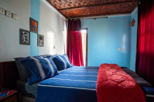 a bedroom with a bed with blue and red at Gite akswal amssakrou in Ikis