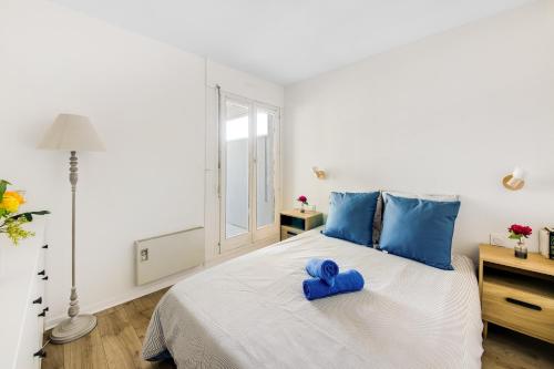 une chambre avec un lit blanc avec des oreillers bleus dans l'établissement La Perle - Vue Mer, Parking Privée Clos, Traversant ,Tv 4K, Fibre, à Canet