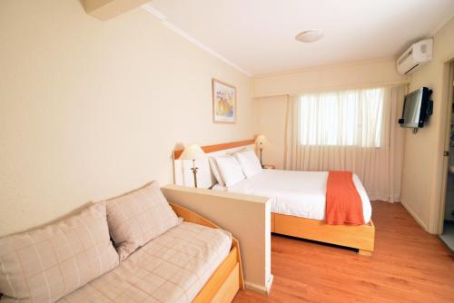 a bedroom with a bed and a couch at Hotel Sunset Beach in Punta del Este