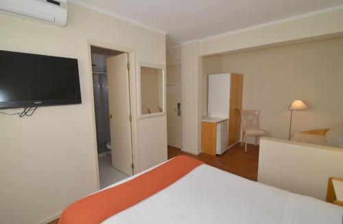 a room with a bed and a television on a wall at Hotel Sunset Beach in Punta del Este