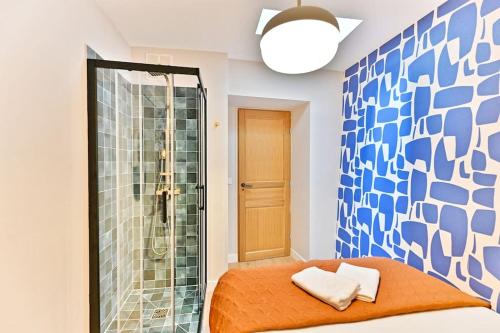La salle de bains est pourvue d'une douche et d'un lit avec des draps orange. dans l'établissement Appartement 3 chambres Paris 2ème - III, à Paris