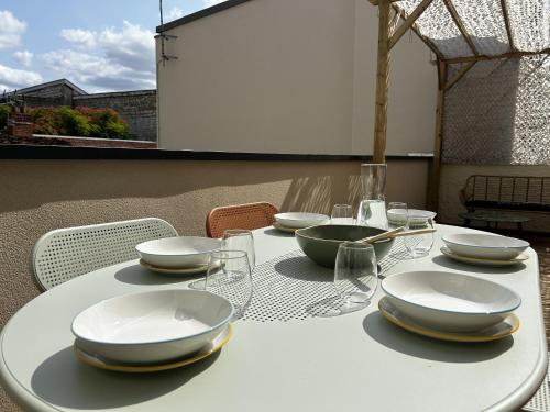 - une table blanche avec des assiettes et des verres dans l'établissement Voie des Sacres - Cathédrale de Reims, à Reims