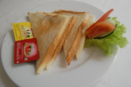 Hotel Dhyana Pura في Kapal: طبق أبيض يعلوه شطيرة وخضروات