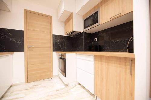 - une cuisine avec des placards en bois et un four micro-ondes dans l'établissement Appartement confortable et moderne - centre, à Levallois-Perret