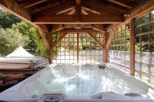a soaking tub in a wooden house with windows at Le moulin de Varax in Saint-Paul-de-Varax