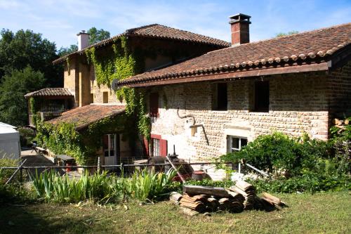 a brick house with a pile of logs in front of it at Le moulin de Varax in Saint-Paul-de-Varax