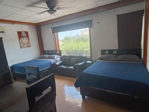 a bedroom with two beds and a couch and a window at Hotel Garcias Suites, Linares in Linares