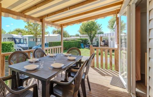 drewniany taras z drewnianym stołem i krzesłami w obiekcie Pet Friendly Stacaravan In Les Mathes w mieście Les Mathes