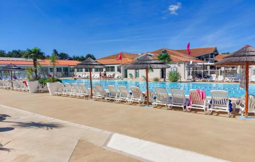 rząd krzeseł i parasoli obok basenu w obiekcie Pet Friendly Stacaravan In Les Mathes w mieście Les Mathes