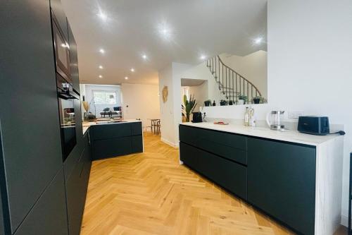 une cuisine avec des armoires noires et un comptoir blanc dans l'établissement La Villa des Platanes Parking Terrasse- WIFI, à Perpignan