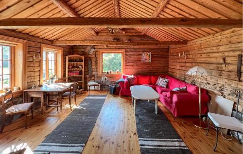 a living room with a red couch in a log cabin at 2 Bedroom Lovely Home In Lindesnes in Lonestranda