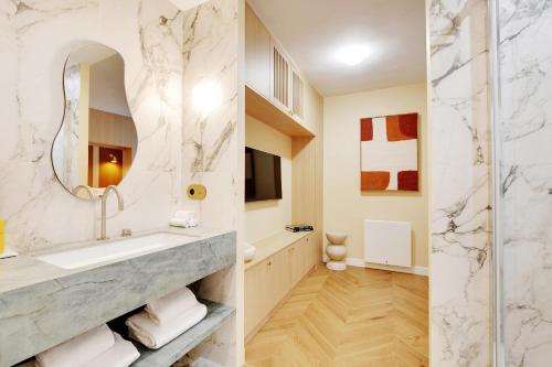 une salle de bain avec un lavabo et un miroir dans l'établissement ONIRI - Serviced Apartment in Place Vendôme, à Paris