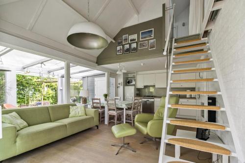 ein Wohnzimmer mit einer grünen Couch und einer Treppe in der Unterkunft Vakantiewoning voor het gezin in Stavenisse in Stavenisse
