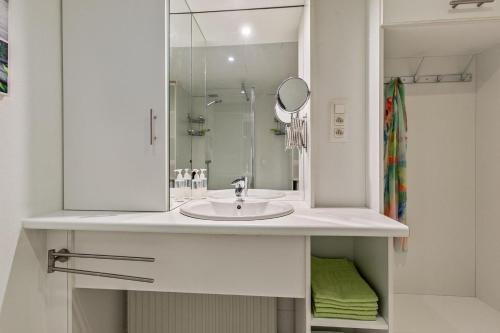 ein weißes Badezimmer mit Waschbecken und Spiegel in der Unterkunft Vakantiewoning voor het gezin in Stavenisse in Stavenisse