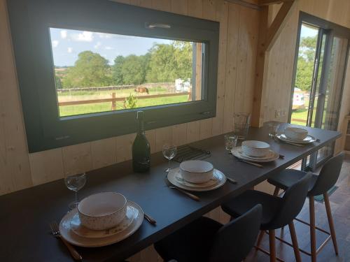 - une table avec des assiettes et des verres à vin ainsi qu'une fenêtre dans l'établissement La Ti'Nid de Jeanne, à Poinson-lès-Fays