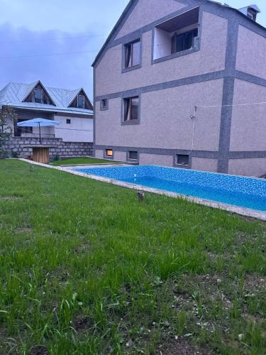 a building with a swimming pool next to a house at Nais House in DILIJAN in Dilijan