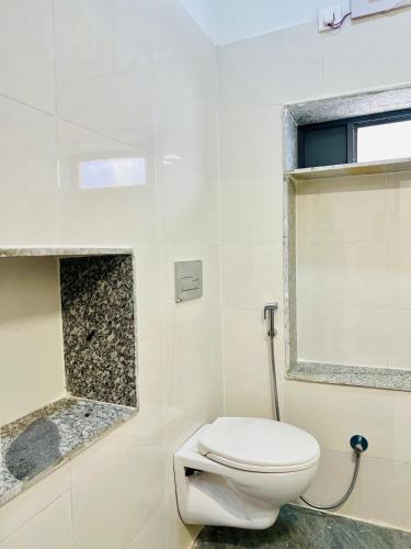 a white bathroom with a toilet and a window at Agariya Pool Villa near Lake pichola in Udaipur