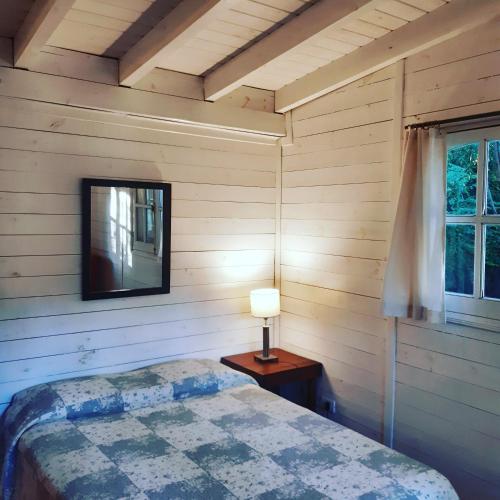 a bedroom with a bed with a lamp and a window at Miralrio in Santa Rosa de Calamuchita