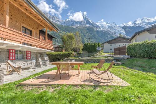 d'une terrasse avec une table, des chaises et des montagnes. dans l'établissement Appartement Couttet - Welkeys, à Chamonix-Mont-Blanc