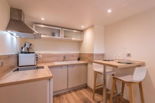 une cuisine avec un évier et un comptoir avec des chaises dans l'établissement Appartement Couttet - Welkeys, à Chamonix-Mont-Blanc