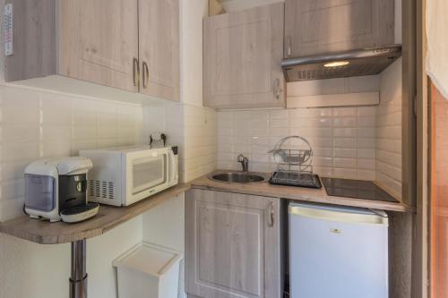 une petite cuisine avec un micro-ondes et un évier dans l'établissement Studio Dryades - Mont Blanc view - Welkeys, aux Houches