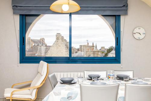 d'une salle à manger avec une table, des chaises et une fenêtre. dans l'établissement Rêves de marins T3 avec parking privé en hyper centre, à Roscoff