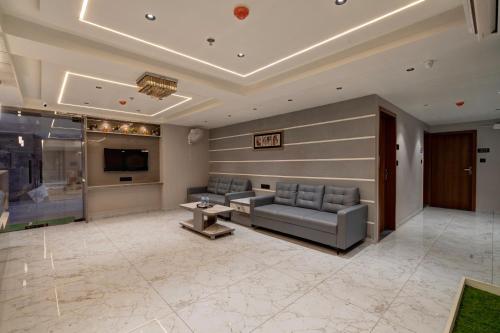 a living room with couches and a tv and a couch at Hotel Shrimad Villa Gandhinagar in Gandhinagar