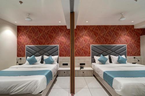 two beds in a hotel room with blue pillows at Hotel Shrimad Villa Gandhinagar in Gandhinagar