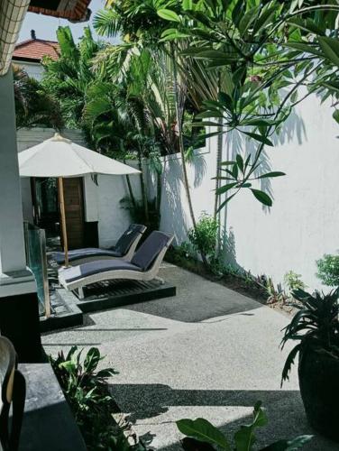 a patio with two lounge chairs and an umbrella at BrightUp Villa Beach Side Sanur in Sanur