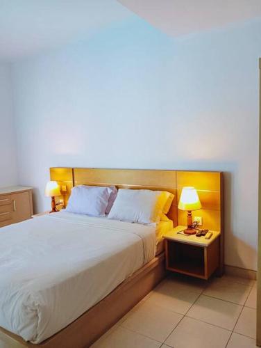 a bedroom with a large bed and two lamps at BrightUp Villa Beach Side Sanur in Sanur