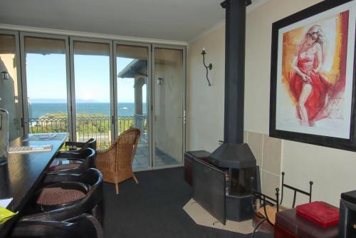 a living room with a fireplace and a view of the ocean at On The Cliff Guest House in Hermanus