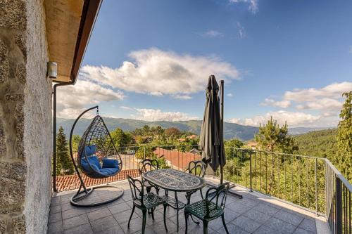 a balcony with a table and chairs and a swing at T1 Panorâmico Ermida in Vilar da Veiga